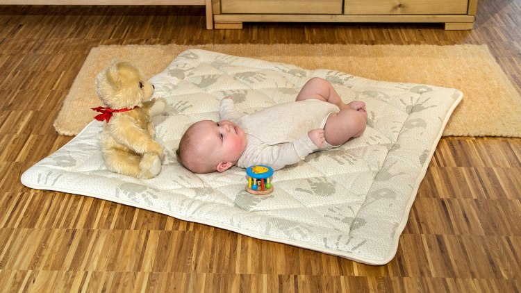 Tapis d'éveil en laine vierge de mouton avec bébé sur le sol